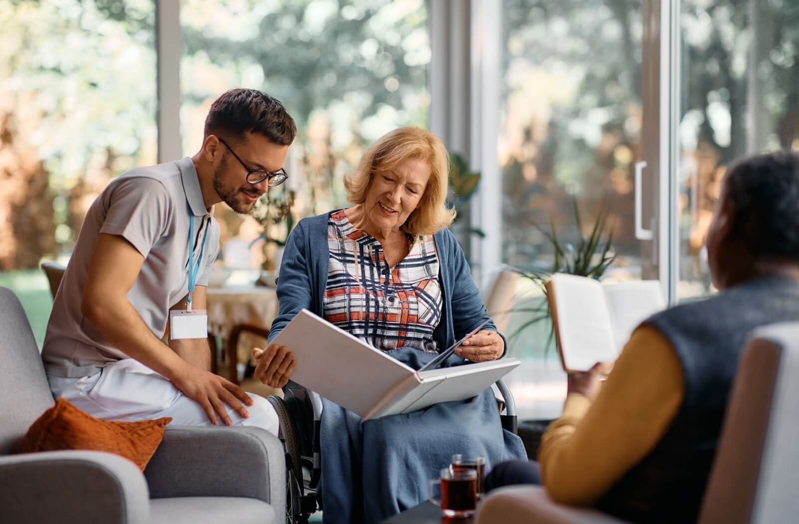 A senior in memory care shows their care provider pictures from a photo album of their life.